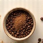 Biji kopi panggang dan butiran gula perang bercampur dalam mangkuk kecil untuk skrub. (Vegan)